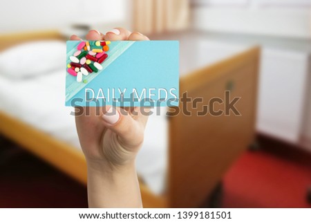 Female medic presenting daily meds text on paper card with pills image closeup