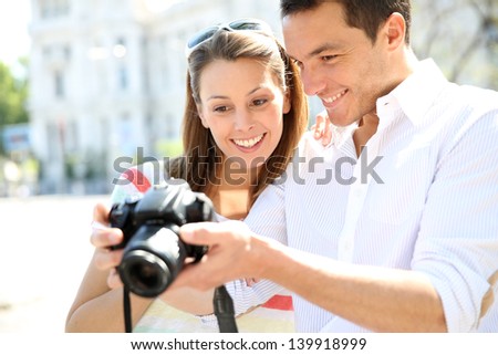 Happy couple looking at pictures on photo camera