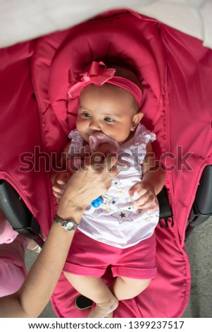 A mother wiping the mouth of her beautiful baby lying on her stroller