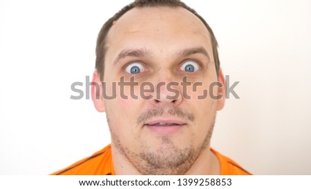 Close-up of a surprised emotional bearded man with blue eyes looking into the camera on a white background