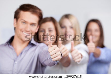 Young businessman and businesswomen showing thumbs up sign in office