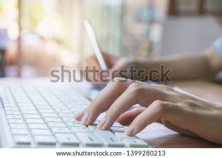 Closeup hand of woman using computer  and writing for business, finance concept in office.