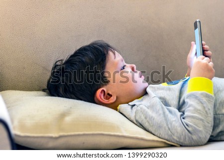 Boy playing smartphone on bed, watching smartphone, young boy use phone and play game, child use mobile, addicted game and cartoon, boy play phone.