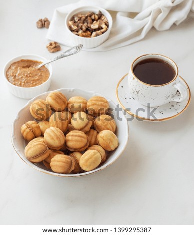 Homemade Russian cookies "Nut". Cookies in the form of a nut from two shells with cream inside. Cookies on plate with tea on white background