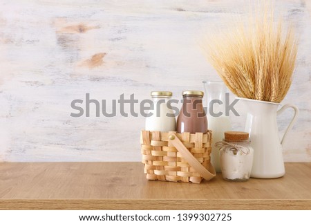 photo of milk and chocolate next to wheat over wooden table and white background. Symbols of jewish holiday - Shavuot