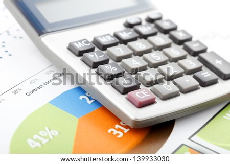 Financial data analyzing. Close-up photo of calculator and diagrams on office desk.  Selective focus