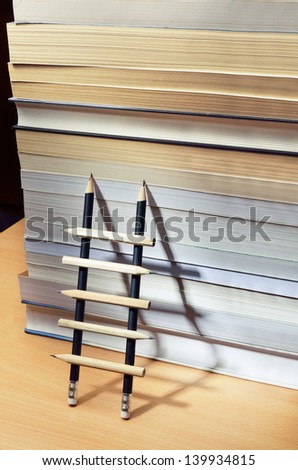 Pencil ladder leaning against a pile of books