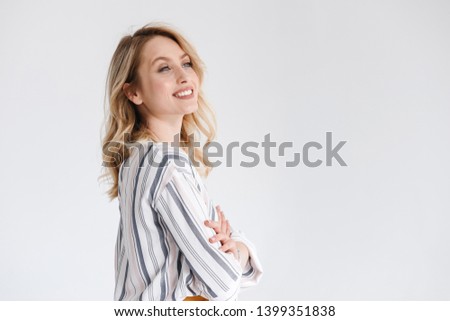 Half turn portrait of young smiling woman wearing casual clothes looking aside at copyspace with arms crossed isolated over white background in studio