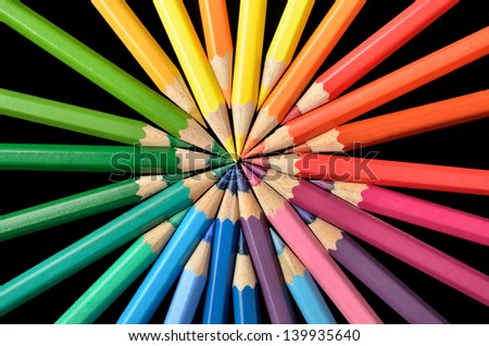 Circular arrangement of colored pencils on black background