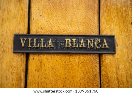 a photo of a name plate "white villa" on a wooden wall.