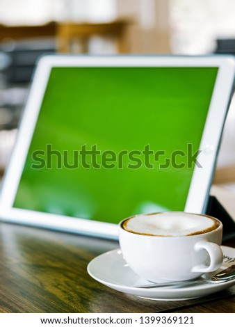 Green screen tablet and coffee mug on table, mock up.