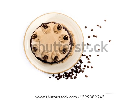Overhead view of Mocha coffee cake with icing swirls on a plate with coffee beans isolated on white