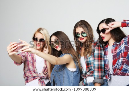 friendship, people and technology concept - four  happy teenage girls with smartphone taking selfie over grey background