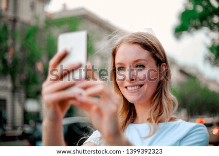 Blonde woman taking a picture with her smartphone.