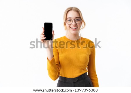 Attractive young blonde woman wearing sweater standing isolated over white background, showing blank screen mobile phone