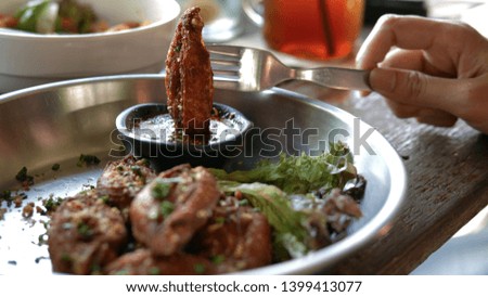 Spicy fried chicken wings. Sprinkle on top with aromatic herbs. Close-up pictures of hands using a fork to eat fried chicken, dip the sauce in the cafe.