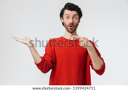 Picture of a handsome young shocked man posing isolated over white wall background pointing.