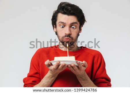 Image of a handsome young excited man posing isolated over white wall background holding birthday cake holidays.