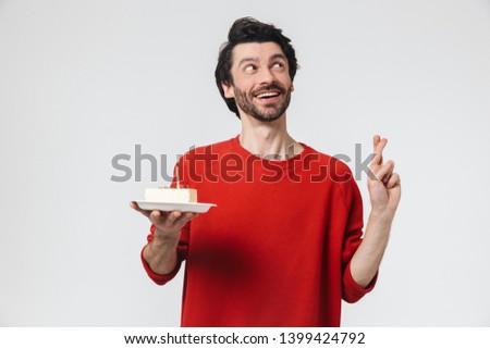 Image of a handsome young excited man posing isolated over white wall background holding birthday cake holidays showing hopeful gesture.