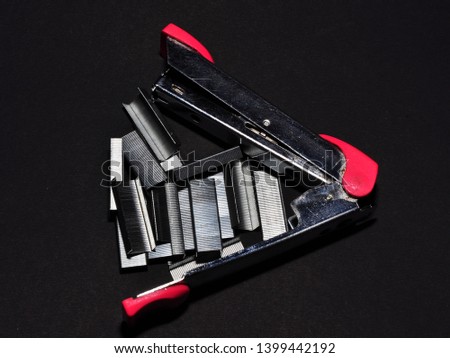 Pink stapler and staples isolated on black background. Office work equipment concept