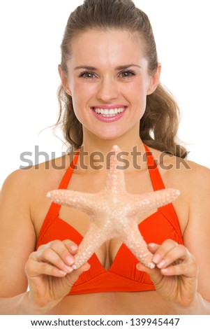 Portrait of smiling young woman in swimsuit showing starfish