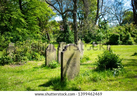 Beautiful graveyard filled with the tombstones (view from the back) of the resting souls of the dead on a peaceful and calm summers day causing feelings of tranquillity and peace. 