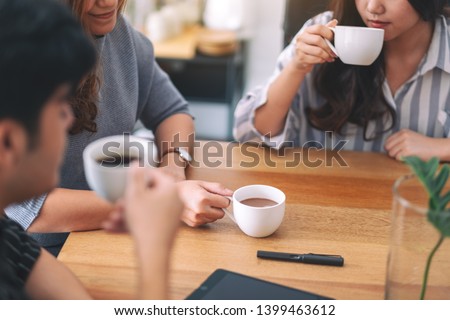 Close up image of three people enjoyed drinking coffee while meeting in office