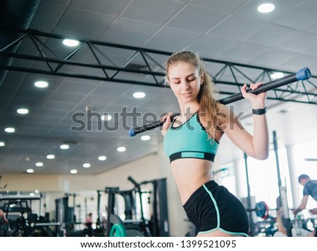 Fitness young blonde woman doing gymnastic exercise with  body bar stick in the gym
