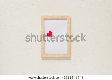 wooden photo frame with red heart on white wall baxkground. Minimal flat lay with copy space