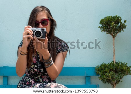 Woman outdoors with sunglasses taking pictures with a retro camera in her hands in Cholula, Mexico