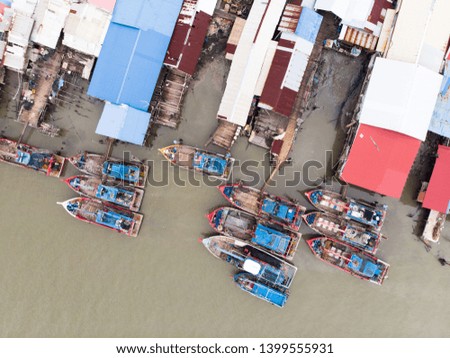 Aerial view of the fisherman village with wooden fish boats and colourful house’s roof at the pier in Kedah,Malaysia.