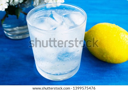 
A glass of cold water with ice and lemon on a blue background