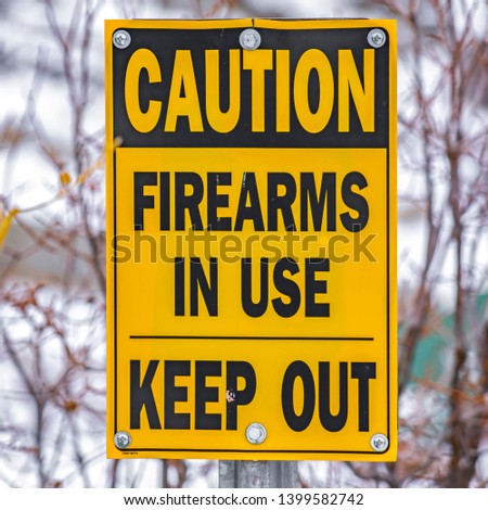 Square Close up of a yellow sign that reads Caution Firearms In Use Keep Out