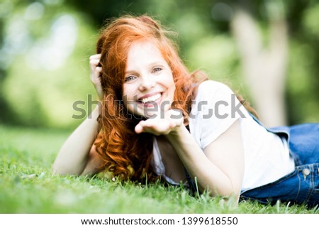 beautiful young redhead woman with blue eyes and freckles with white t-shirt and lacy jeans is having fun
