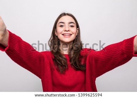 Portrait of a smiling woman making selfie photo on smartphone isolated on a white background
