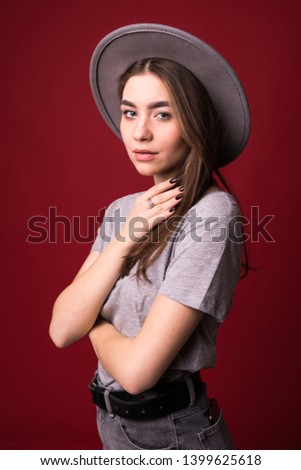 Young pretty woman with gray hat standing isolated on red background