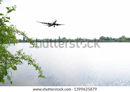 The plane flies over a large lake in nature. The evening in the summer

