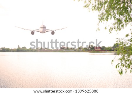The plane flies over a large lake in nature. The evening in the summer
