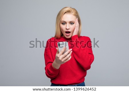 Closeup portrait amazed young girl looking at phone isolated on gray wall background. Human reaction