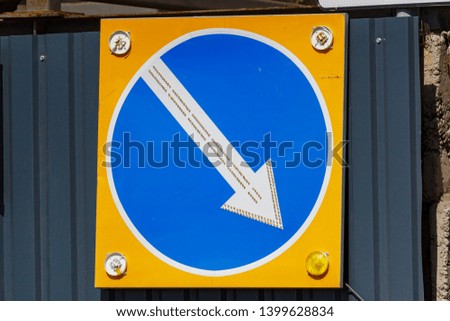 Temporary road sign with arrow indicating the direction of detour closeup