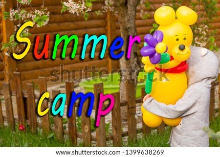 little girl holding large yellow bear from balloons with a big flower in the garden, congratulations on the occasion. Summer camp