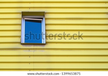 An isolated window on a yellow facade of an apartment house