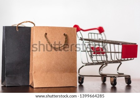 Paper shopping bags and shopping cart on wooden table