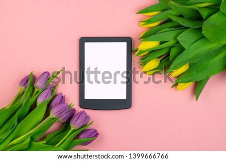 Tulips background. Bunch of purple and yellow tulip flowers with tablet for mock up on pink pastel background. Spring flowers banner