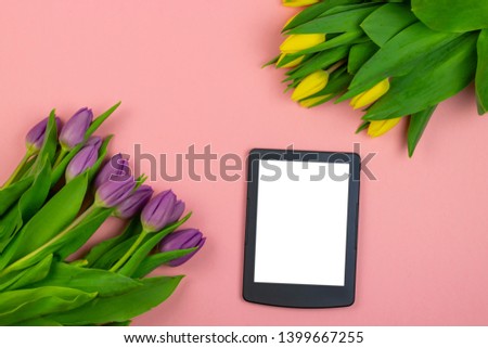 Tulips background. Bunch of purple and yellow tulip flowers with tablet for mock up on pink pastel background. Spring flowers banner