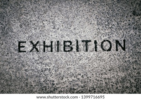 "EXHIBITION" written on asphalt or concrete wall, sign written in black letters