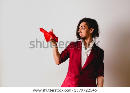 Portrait of young magician handling ropes and bandanas to do magic tricks, isolated on white.