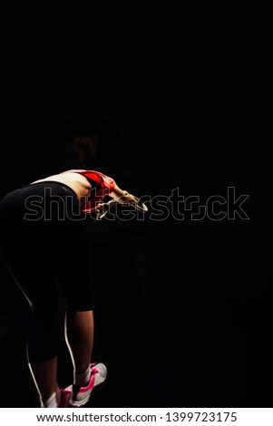 Fit, sporty and athletic girl working in gym center, low key dark image