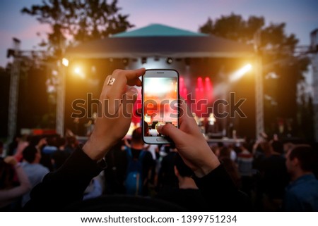 Hands with a smartphone records live music festival, Taking photo of concert stage