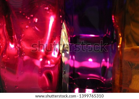Picture of a pink, purple and orange glasses of water with light effects.